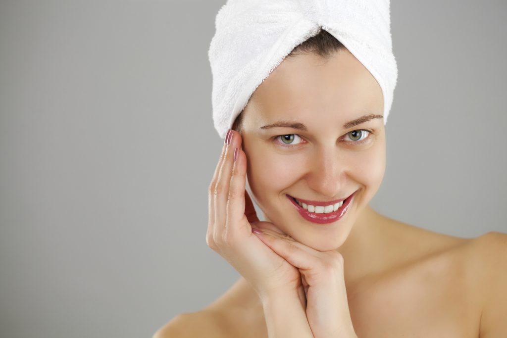 Body Care. Beautiful young woman posing in white towel. Spa, healthcare. isolated on grey background